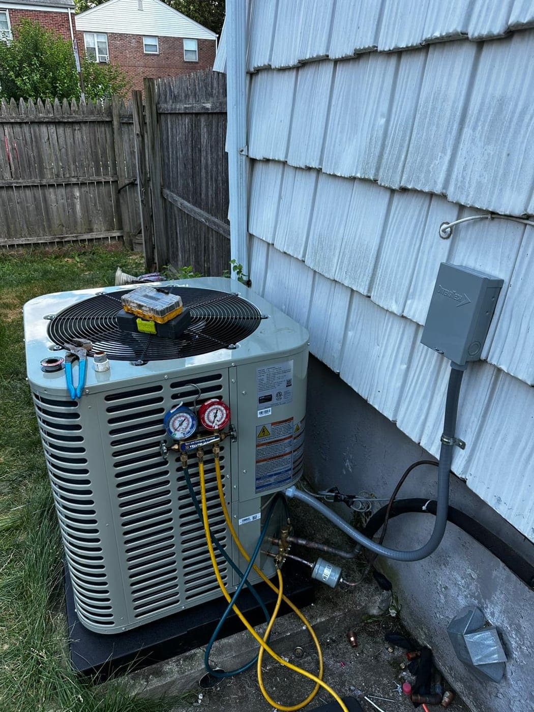 Refrigerant gauges connected to a residential air conditioning condenser during a repair