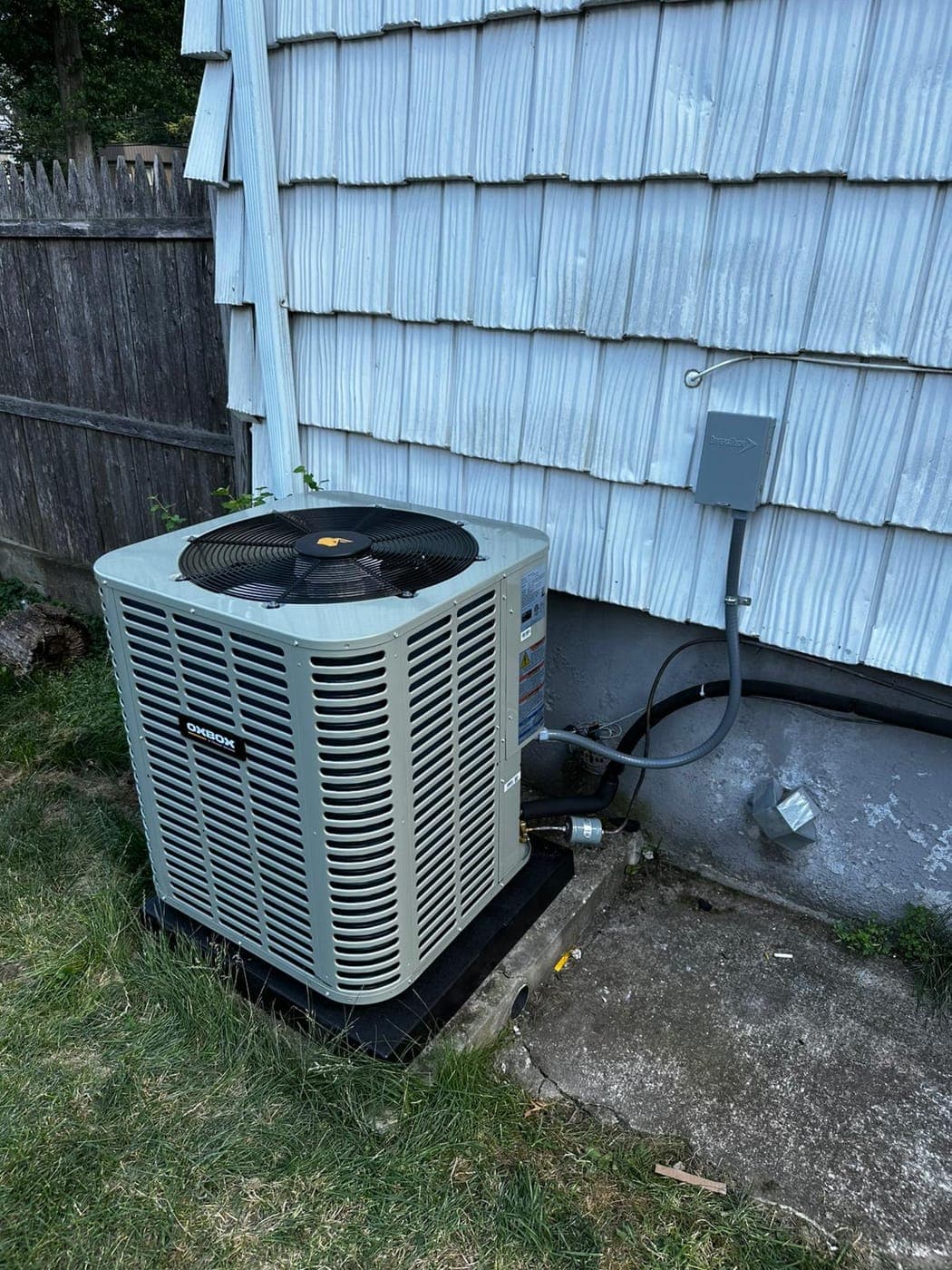 New central air conditioning condenser installed on a pad beside a North Jersey home