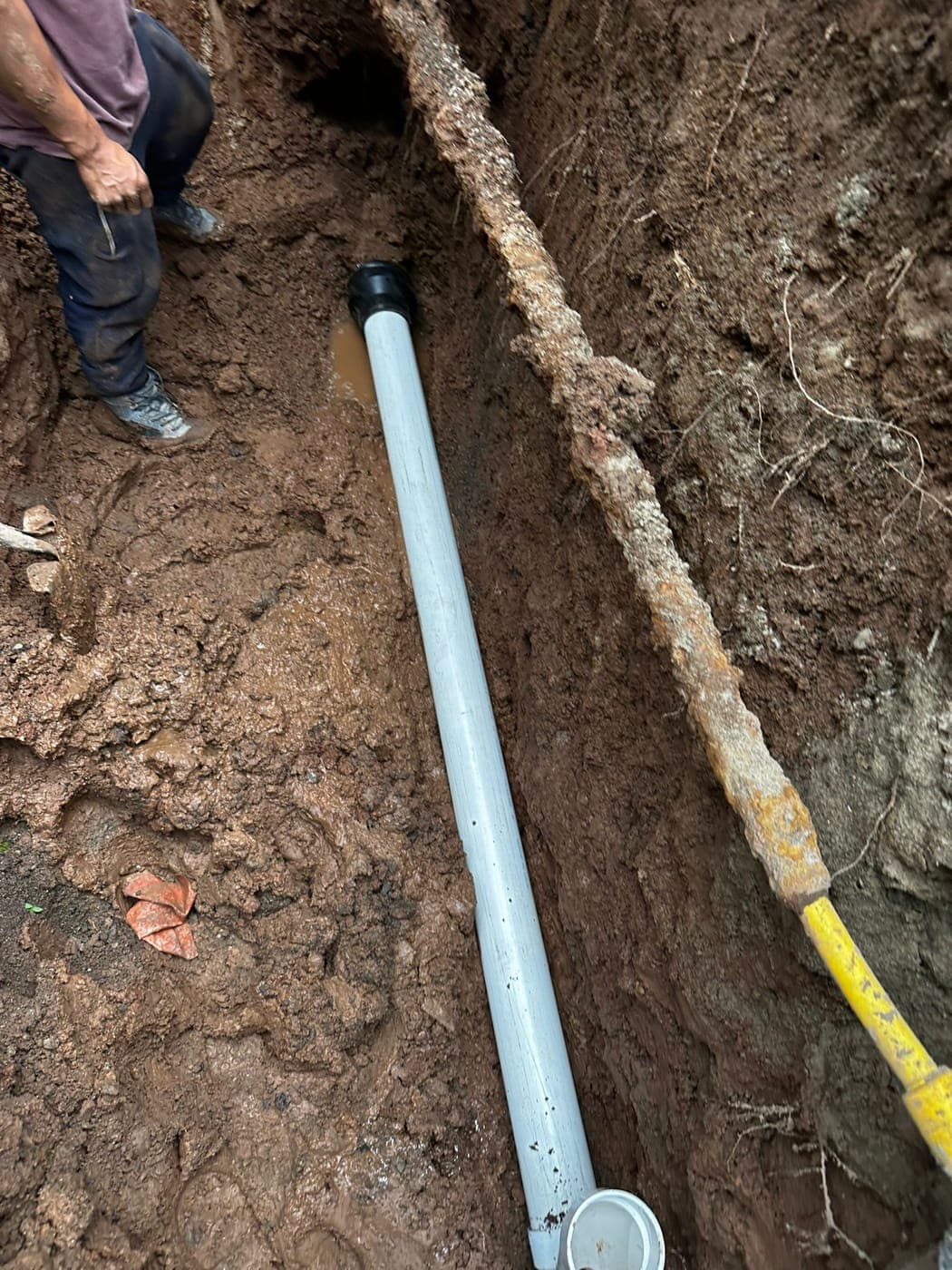 New PVC sewer line installed in an open trench beside a home