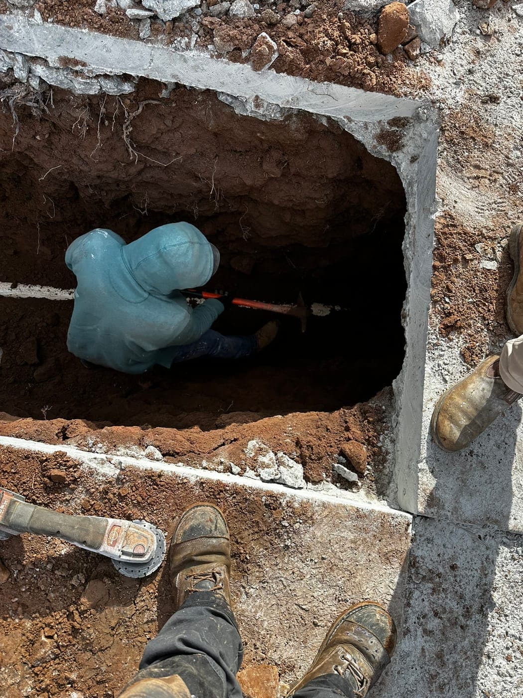 Technician digging a sewer trench by hand